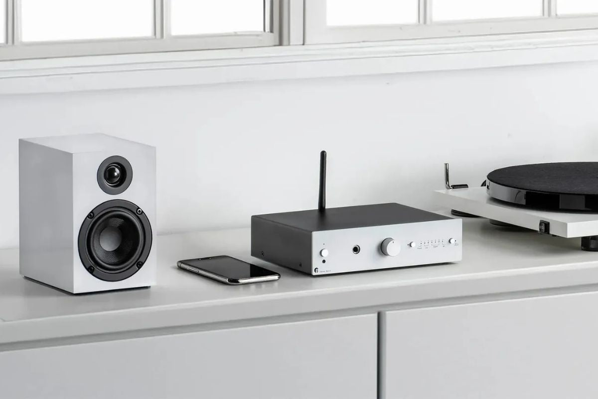 Pro-Ject HiFi-Setup mit Regallautsprecher, Verstärker und Plattenspieler auf einem Sideboard.